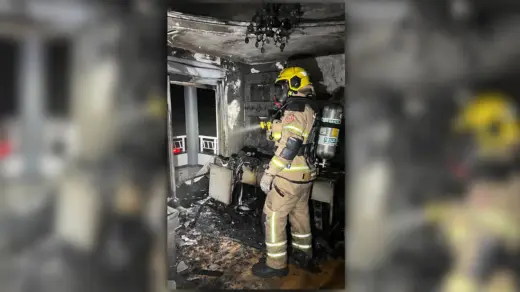 Bombeiro com equipamento de proteção no interior de cômodo atingido pelo incêndio em Veranópolis.